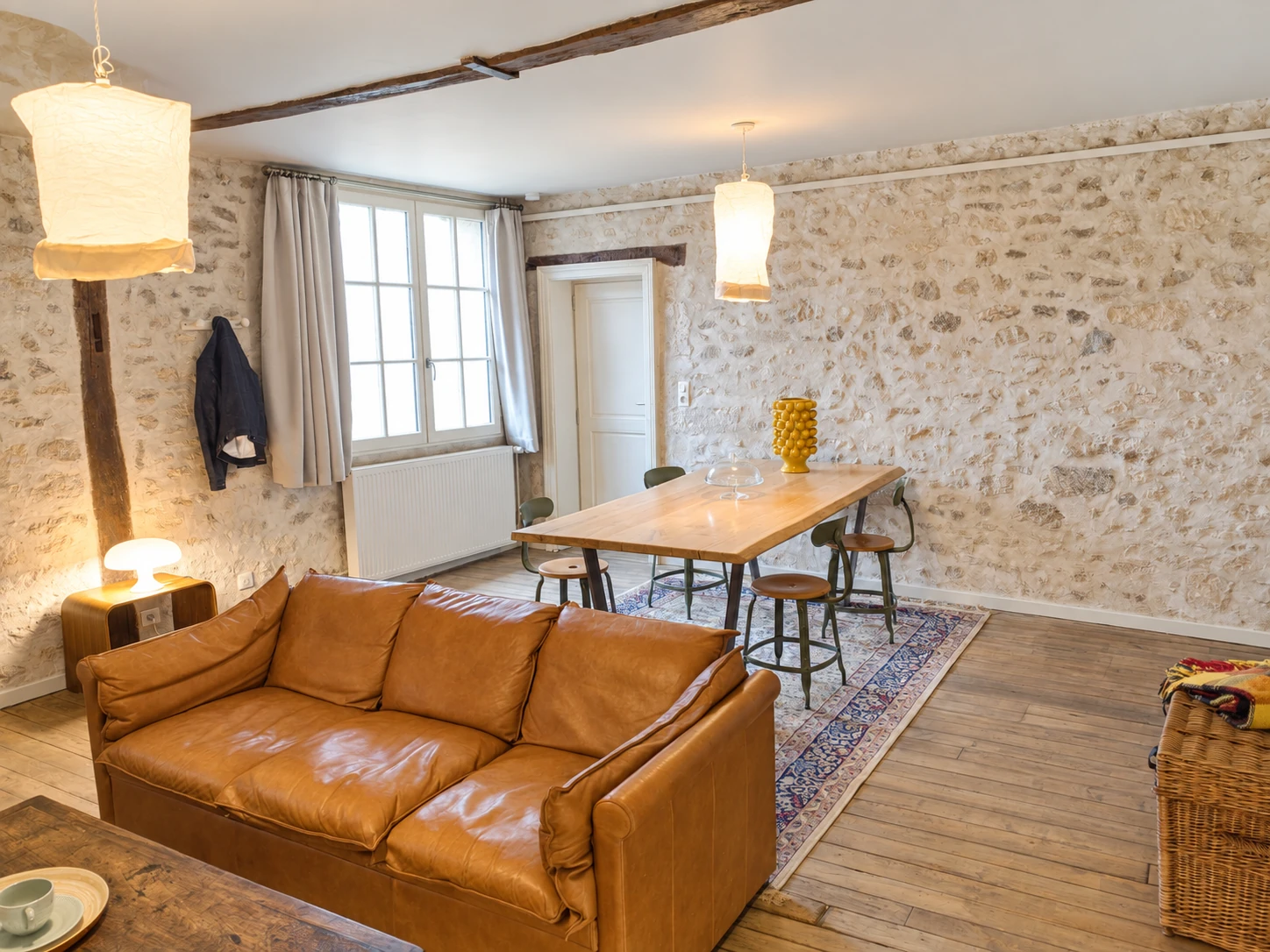 Le salon et le coin repas de l’appartement n°6, avec canapé en cuir et murs en pierre